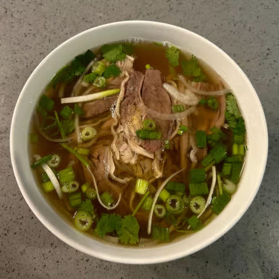 A bowl of Pho Teresa's Vietnamese pho with beef, noodles, and fresh herbs.