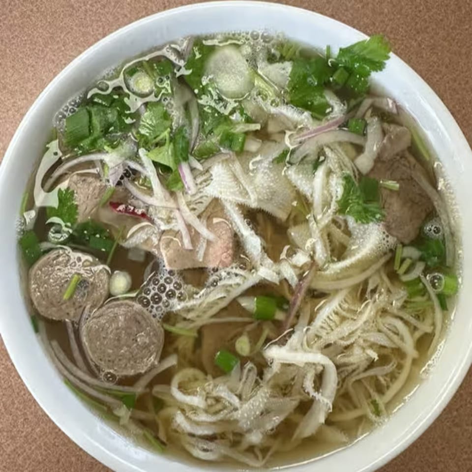 Close-up of a bowl of Pho Teresa's Vietnamese pho with noodles, beef, tripe, and herbs.